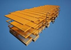 Large yellow industrial steel structure viewed from below against vast blue sky.