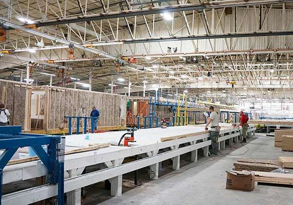 A modular construction warehouse where construction workers are building module frames